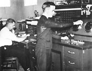 McMullen and A. J. Silk (standing) at the P.B.X. and Fire Alarm Control Desks.